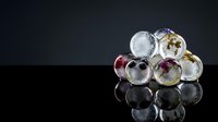 Frozen berries and flowers suspended in ice spheres arranged on reflective black surface, showcasing natural ingredients for culinary, beverage, and design projects.