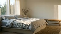 Serene bedroom interior with natural light from large window, neutral tones, minimalist decor, and cozy bedding arrangement for home design and lifestyle content.