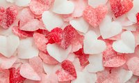 Pink and white sugar coated heart shaped jelly candies scattered on light background, romantic sweet dessert pattern for Valentine's day celebration.