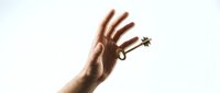 Hand holding vintage brass key against bright light creating dramatic silhouette effect for success and opportunity concepts in business presentations.