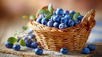 Fresh blueberries in wicker basket with green leaves on wooden table, natural organic berries for healthy eating and desserts.