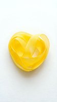 Yellow ribbon twisted into heart shape on white background isolated for romantic design projects and Valentine's Day decorations.