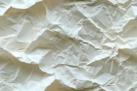 Crumpled white paper texture with deep shadows and wrinkles creating an abstract pattern of folds and creases, suitable for backgrounds and design elements.
