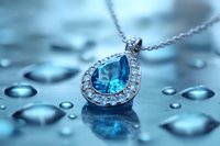 Elegant teardrop pendant necklace with blue topaz gemstone and diamond halo on reflective surface with water drops creating luxurious jewelry atmosphere.