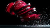 Sliced red apple with water droplets and splash on black background for healthy eating and nutrition concepts.