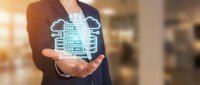 Businesswoman presenting digital cloud computing technology with data storage icons floating above her palm in modern office environment.