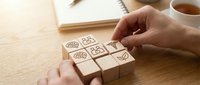 Hand arranging wooden blocks with eco-friendly symbols on desk. Sustainable business concept with environmental icons for green marketing materials.