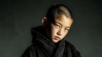 Young Asian man in black hoodie with serious expression against dark background for fashion and lifestyle projects.