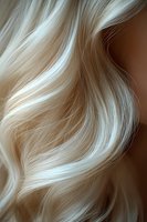 Flowing platinum blonde wavy hair strands with soft highlights and natural movement against dark background, macro close-up view for beauty and haircare advertising.