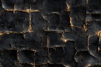 Dark cracked surface with golden light glowing through fissures creates dramatic abstract pattern. Textured black background with illuminated fractures for design.