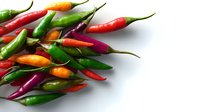 Fresh colorful chili peppers scattered on white background, including red, green, orange and purple varieties. Spicy ingredients for cooking and food decoration.