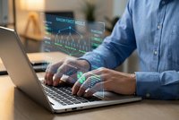 Businessman analyzing financial data with holographic charts and graphs on laptop screen in modern office environment for investment decisions.
