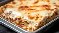 Of pasta, meat sauce, and melted cheese in baking dish, close-up view showing golden brown top and rich filling texture.