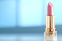Pink lipstick in luxurious golden case against soft blue background, elegant cosmetic product photography for beauty and makeup advertising.