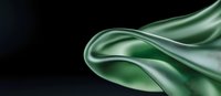 Elegant flowing green silk fabric creating smooth waves and folds against dark background, abstract luxury textile design for fashion and decor.