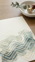 Elegant gold foil chevron pattern on white paper with eucalyptus and ceramic bowl, luxury stationery design for wedding invitations and branding materials.