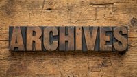 Vintage wooden letterpress blocks spelling ARCHIVES on rustic wood background for historical documentation and storage concepts.