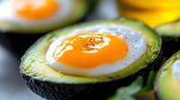 Sunny side up egg baked in fresh avocado half, close-up view of healthy breakfast option with protein and healthy fats.