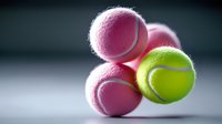 Colorful tennis balls stack with pink and green sports equipment on white surface for athletic training and recreation activities.