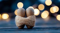Two wooden figures bound together with twine against blurred golden bokeh lights creating romantic atmosphere on dark background.