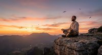 Young man meditating on mountain cliff at sunset with birds flying overhead. Peaceful mindfulness practice in nature with dramatic orange sky and valley view.
