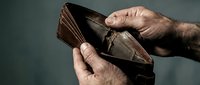 Empty worn leather wallet held by elderly male hands showing financial hardship and poverty concept for economic struggles.