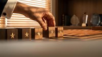 Hand placing wooden blocks with star symbols in row on desk for customer service rating and quality assessment in warm office environment.