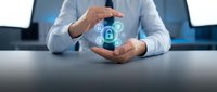Businessman in light blue shirt holding hands around glowing padlock icon, representing data protection, cybersecurity, and digital safety for business applications.