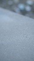 Close-up of frost-covered surface with shallow depth of field, showing crystalline ice formations and blurred frozen background for winter themes.