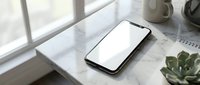 Modern smartphone with blank white screen mockup on marble desk surface near window with natural lighting for app presentation and digital design projects.