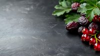 Fresh red cherries with green leaves on dark slate background for culinary photography and food styling projects.