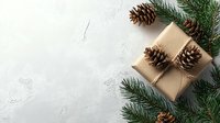 Eco-friendly Christmas gift wrapped in craft paper with natural pine cones and green fir branches on white textured background with copy space.