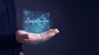 Businessman holding glowing holographic data analytics chart with upward trending graph lines, representing financial growth, digital technology, and business intelligence solutions.