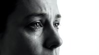 Emotional black and white portrait of crying woman with tears streaming down face showing deep sadness and vulnerability in dramatic lighting.