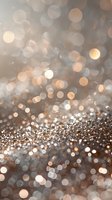 Magical glowing bokeh lights in soft beige and silver tones create dreamy abstract background with sparkling glitter effect for festive holiday designs.