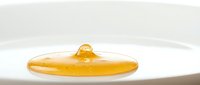 Golden honey drip on white surface, isolated sticky liquid drop for food, cooking, and wellness design projects.