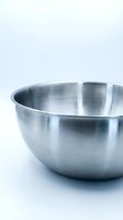 Shiny stainless steel mixing bowl isolated on white background, empty kitchen utensil for cooking, baking, and food preparation.