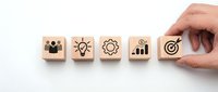 Hand placing wooden cube with target icon completing business strategy concept row on white background for corporate planning and goal achievement.