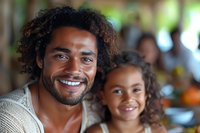 Smiling African American father and daughter with curly hair enjoying family time together in warm, blurred restaurant setting.