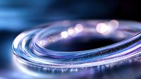 Glowing curved line with sparkles and bokeh effects in blue and purple tones against dark background creates futuristic technological atmosphere.