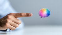 Male hand pointing at colorful rainbow speech bubble floating in air against light background, representing creative communication and innovative ideas.