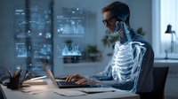 Middle-aged Asian businessman working at laptop with digital medical interface showing skeletal system and health analytics data in modern office.