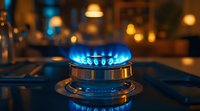 Blue gas flame burning on modern kitchen stove with dark background and warm ambient lighting, close up view showing energy consumption and cooking concept.