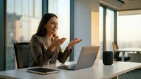Professional businesswoman having video call in modern office with laptop and smart speaker on desk during golden hour lighting.