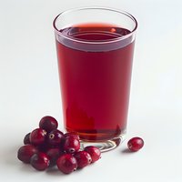 Fresh cranberry juice in clear glass with scattered ripe berries on white background, natural antioxidant drink for healthy lifestyle and nutrition.