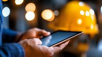 Person holding smartphone in dark setting with blurred golden bokeh lights in background, creating atmospheric evening mood for mobile technology and connectivity concepts.