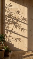 Sunlight casting bamboo leaf shadows on light wooden wall with potted plant and woven floor mat in minimalist interior space.