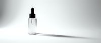Clear glass dropper bottle with black pipette cap on white background, isolated cosmetic serum container for skincare, beauty product packaging, and medical or pharmaceutical applications.