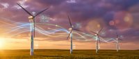 Wind turbines generating clean energy with flowing light trails against dramatic sunset sky over green field for renewable power concepts.