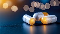 White pharmaceutical capsules with golden light reflection on dark surface against blurred bokeh background creating magical medical atmosphere.